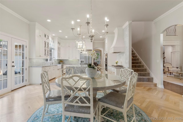 dining space with french doors, crown molding, sink, a notable chandelier, and light parquet flooring