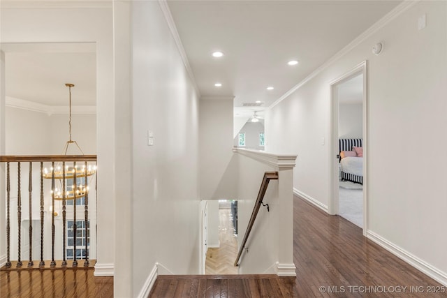 hallway with wood-type flooring, a chandelier, and ornamental molding