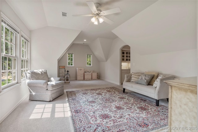 carpeted living room with ceiling fan, plenty of natural light, and vaulted ceiling