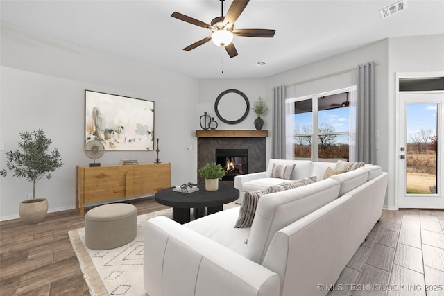 living room featuring a high end fireplace and ceiling fan