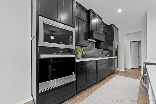 kitchen with ceiling fan, stainless steel appliances, light hardwood / wood-style floors, and decorative backsplash