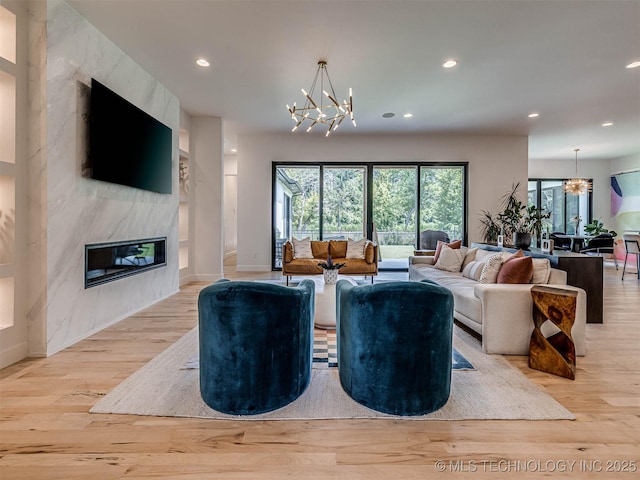 living room featuring a fireplace, light hardwood / wood-style floors, and an inviting chandelier