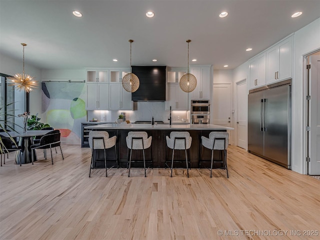 kitchen featuring premium range hood, pendant lighting, white cabinets, and stainless steel appliances