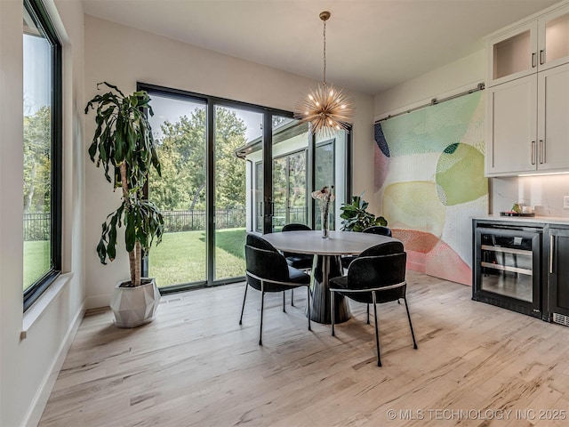 dining area with light hardwood / wood-style flooring, beverage cooler, and a chandelier