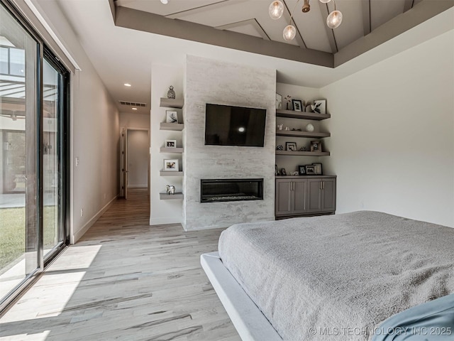 bedroom featuring access to exterior, light hardwood / wood-style floors, and a fireplace