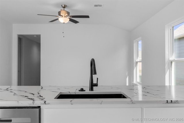 room details featuring ceiling fan, light stone counters, white cabinetry, and sink