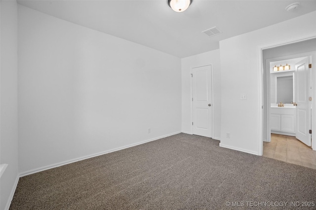 unfurnished bedroom with light colored carpet and connected bathroom