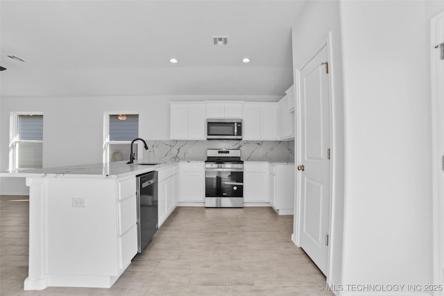 kitchen with appliances with stainless steel finishes, backsplash, white cabinetry, and sink