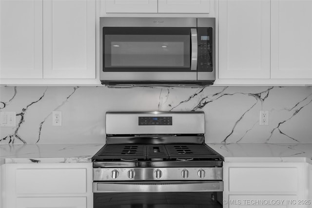 kitchen featuring white cabinetry, decorative backsplash, stainless steel appliances, and light stone counters