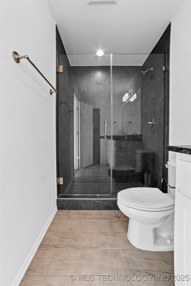 bathroom featuring a shower with shower door and toilet