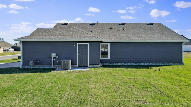 rear view of property with a lawn and central AC