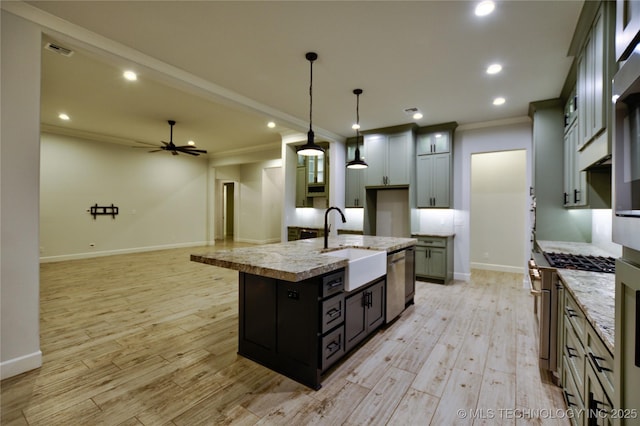 kitchen with dishwasher, a center island with sink, sink, hanging light fixtures, and ceiling fan