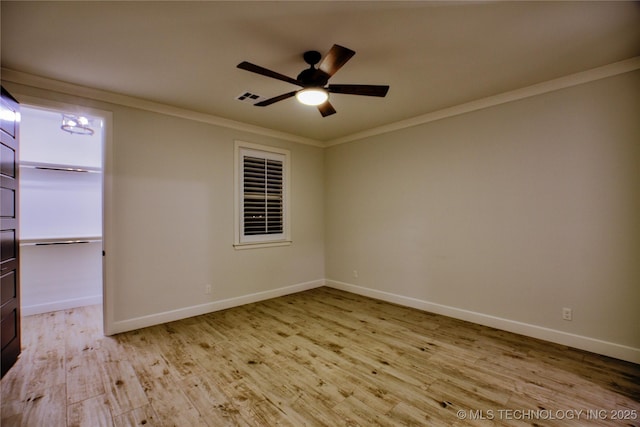 empty room with ceiling fan with notable chandelier, light wood-type flooring, and crown molding