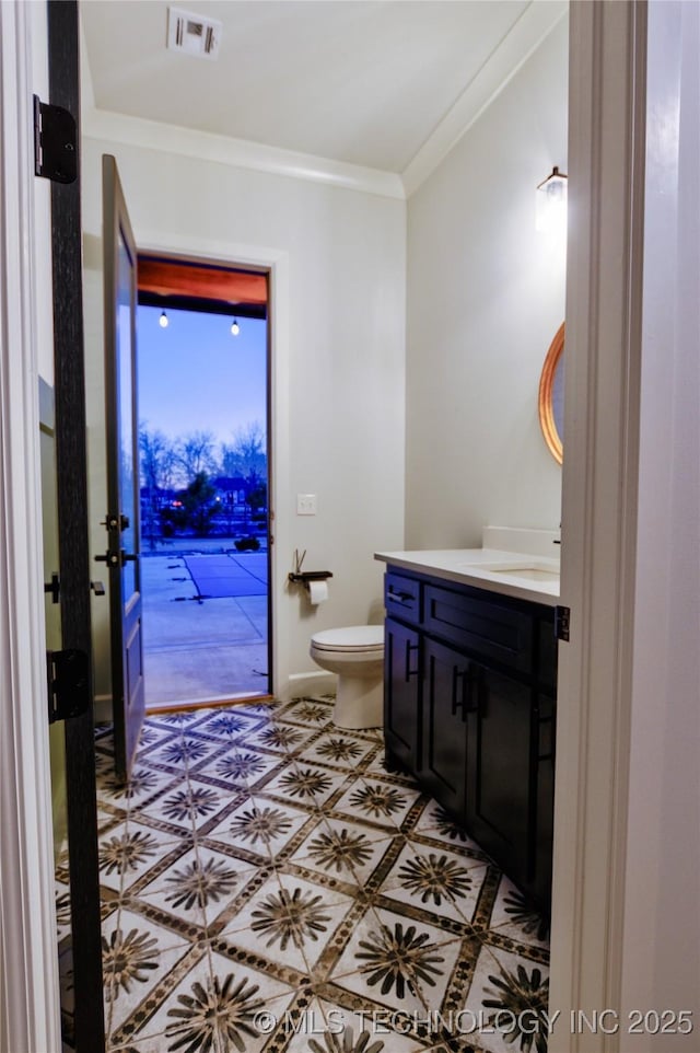 bathroom featuring tile patterned flooring, vanity, toilet, and crown molding