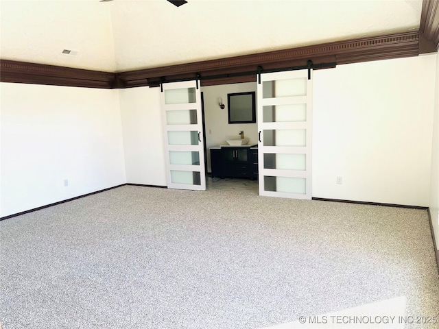 unfurnished living room with a barn door, carpet flooring, and sink