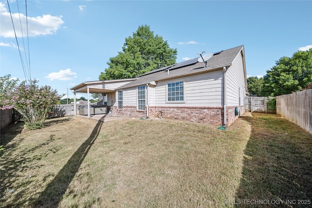 rear view of property with a lawn, a patio, and solar panels