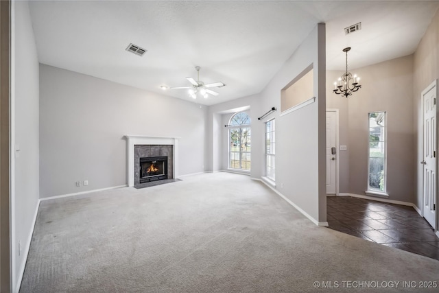 unfurnished living room featuring a fireplace, ceiling fan with notable chandelier, dark carpet, and a barn door