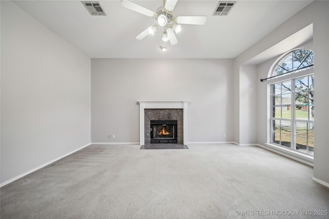 unfurnished living room featuring carpet, ceiling fan, and a tiled fireplace