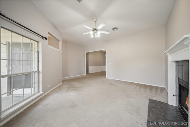 unfurnished living room with carpet, ceiling fan, and a tile fireplace