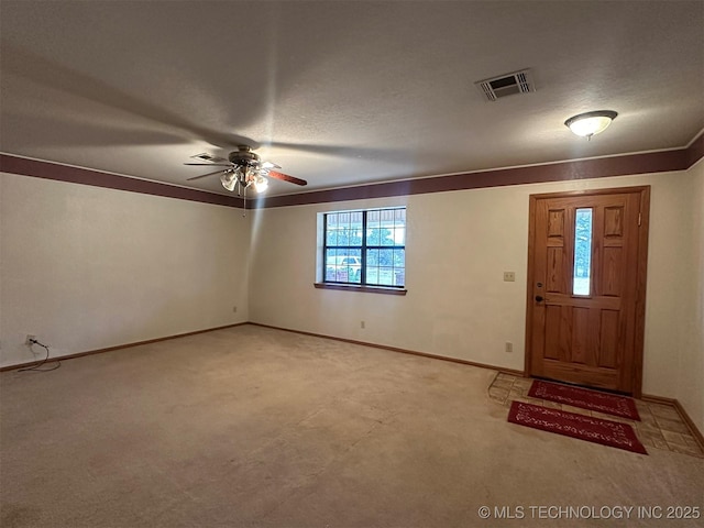 carpeted foyer entrance with a textured ceiling and ceiling fan