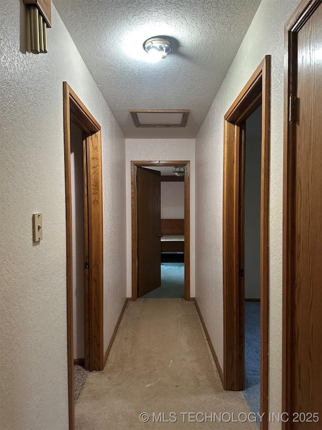 corridor featuring a textured ceiling and light carpet