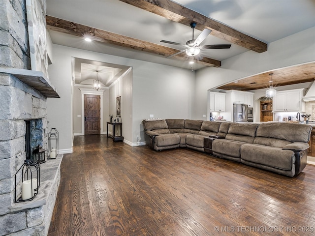 living room with beam ceiling, a fireplace, ceiling fan with notable chandelier, and dark hardwood / wood-style flooring