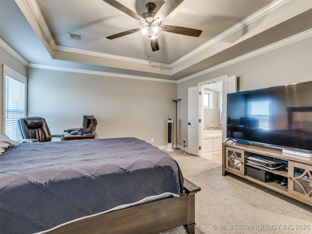 bedroom with a raised ceiling, connected bathroom, light colored carpet, and ceiling fan