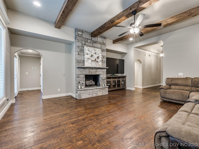 living area with a stone fireplace, wood finished floors, arched walkways, and baseboards