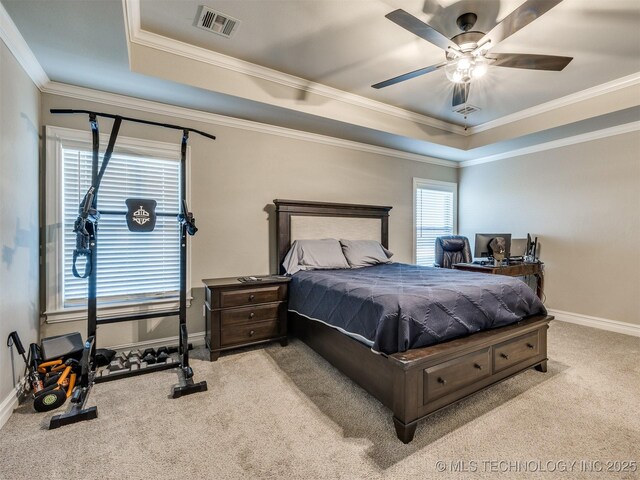 bedroom featuring light carpet, a tray ceiling, multiple windows, and ceiling fan