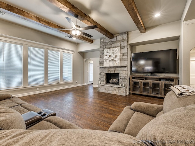 living area with wood finished floors, arched walkways, a stone fireplace, baseboards, and ceiling fan