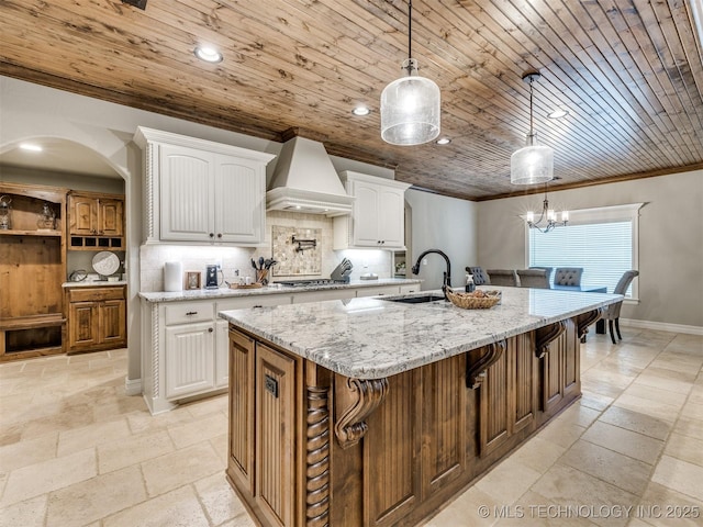 kitchen with custom exhaust hood, stone tile flooring, ornamental molding, wood ceiling, and backsplash