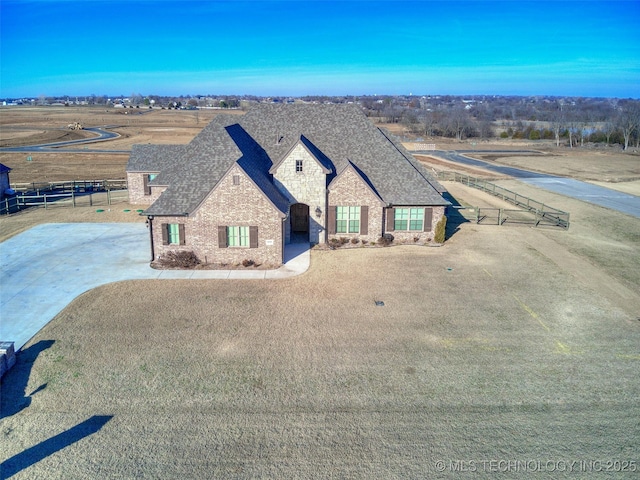 view of front of home featuring brick siding, roof with shingles, driveway, and fence