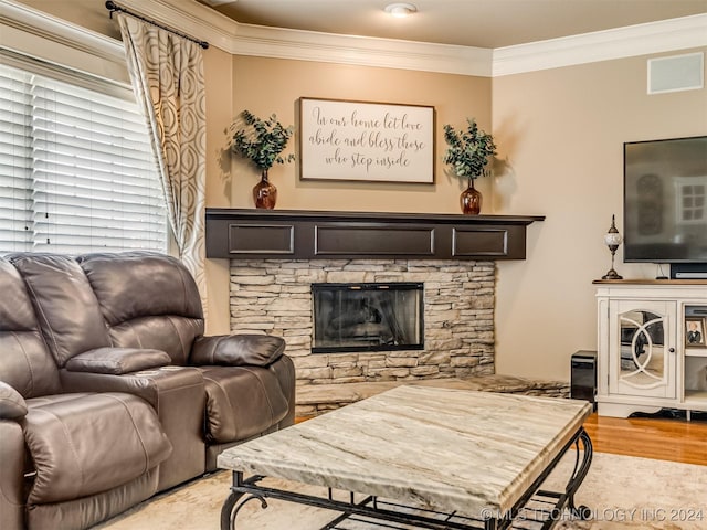 living room with a stone fireplace, ornamental molding, and hardwood / wood-style floors