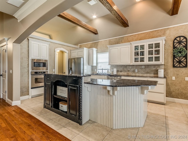 kitchen with a breakfast bar area, white cabinetry, stainless steel appliances, and a kitchen island