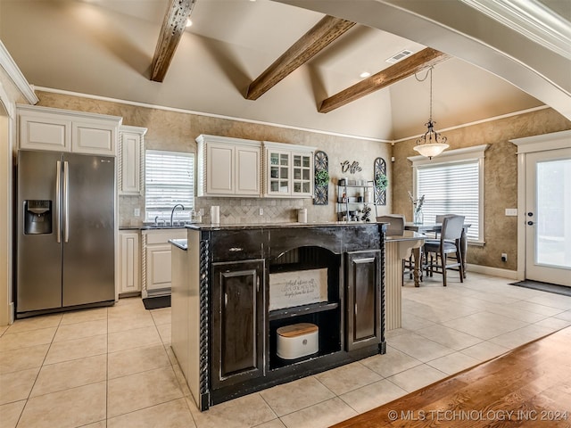 kitchen featuring dark stone countertops, a kitchen island, vaulted ceiling with beams, light tile patterned flooring, and stainless steel fridge with ice dispenser