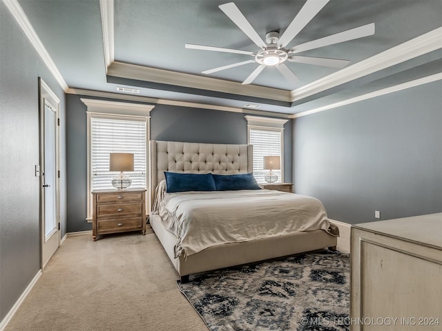 bedroom featuring ceiling fan, ornamental molding, a tray ceiling, and multiple windows