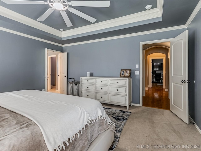 carpeted bedroom with ceiling fan, crown molding, and a raised ceiling