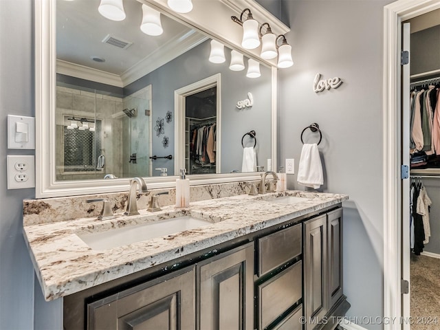 bathroom featuring a shower with shower door, vanity, and ornamental molding