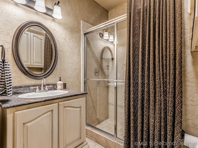 bathroom with a shower with shower door and vanity