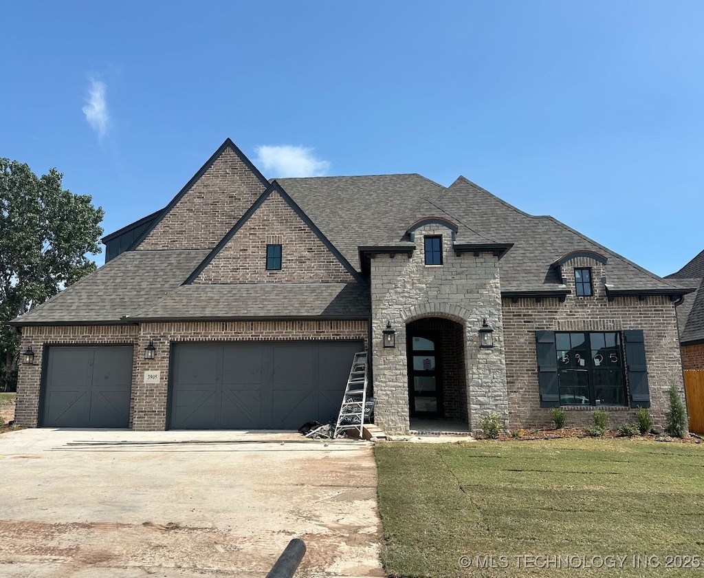 french country style house with a front yard and a garage