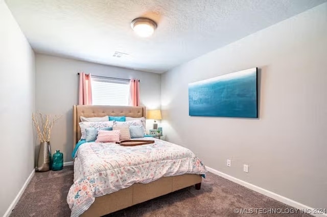 bedroom with dark carpet and a textured ceiling