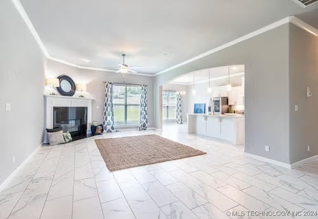 unfurnished living room with ceiling fan and crown molding