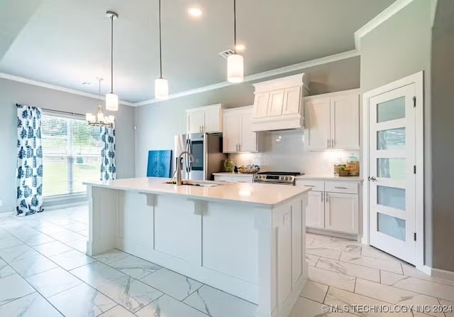 kitchen with white cabinets, decorative light fixtures, a center island with sink, and stainless steel appliances