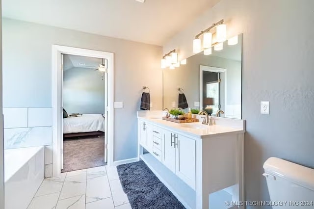 bathroom featuring vanity, a tub to relax in, and toilet