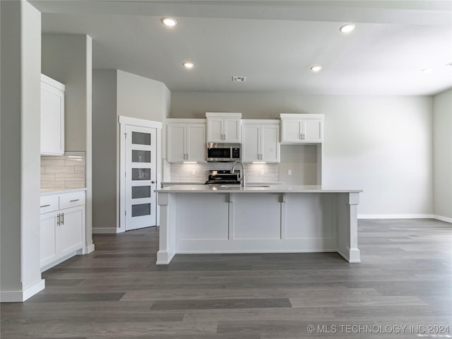 kitchen featuring white cabinets, range, and an island with sink