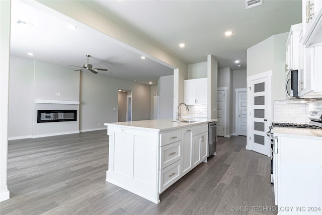 kitchen with appliances with stainless steel finishes, tasteful backsplash, wood-type flooring, white cabinetry, and an island with sink