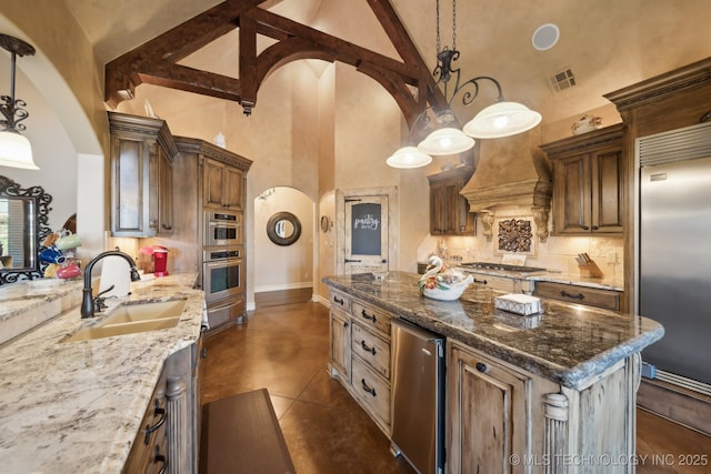 kitchen featuring arched walkways, a sink, appliances with stainless steel finishes, light stone countertops, and decorative light fixtures