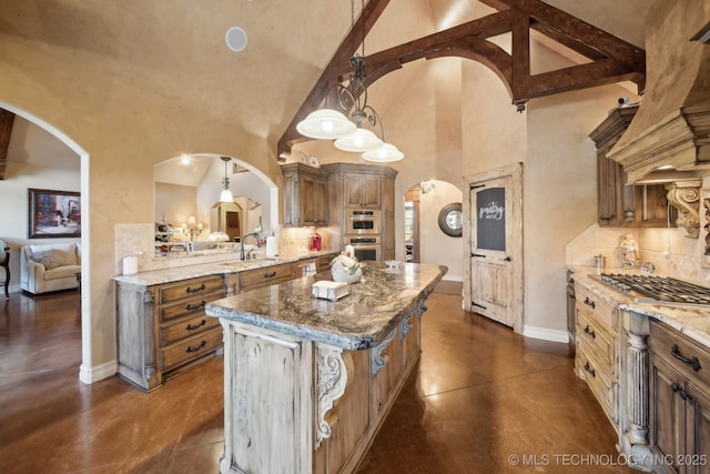 kitchen with a towering ceiling, arched walkways, light stone counters, and appliances with stainless steel finishes