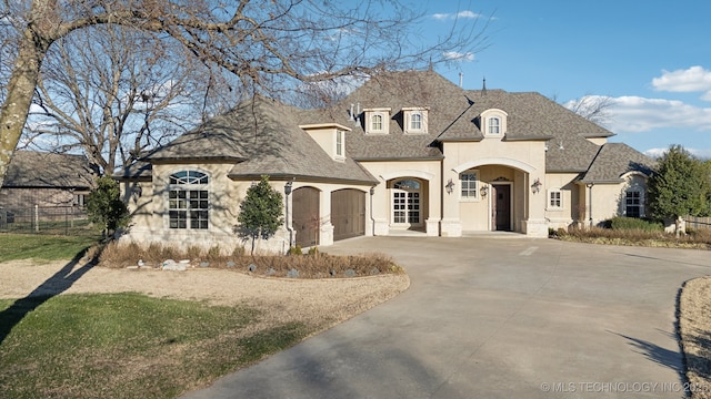 french provincial home featuring driveway, a shingled roof, a garage, and stucco siding