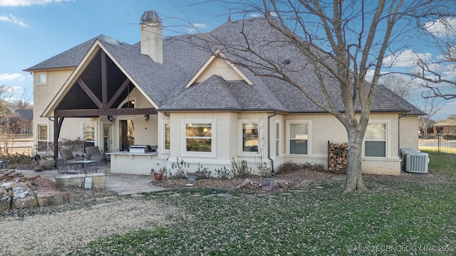 view of front of house with a shingled roof, a patio, a chimney, exterior kitchen, and stucco siding